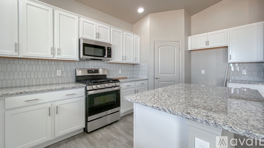 A kitchen with white cabinets and a granite countertop.