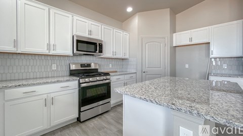 A kitchen with white cabinets and a granite countertop.