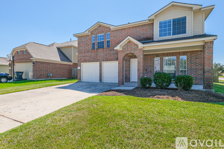 A house with a brick facade and a large driveway is for sale.