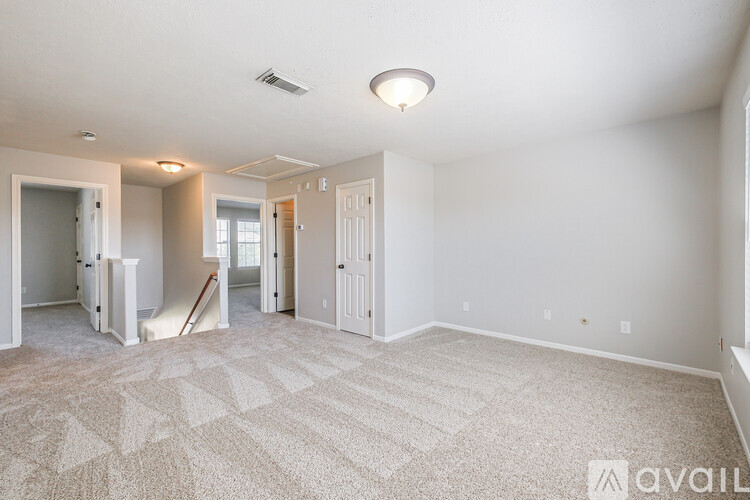A spacious room with a carpeted floor and white walls.