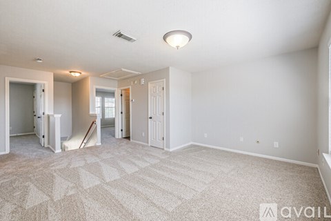 A spacious room with a carpeted floor and white walls.