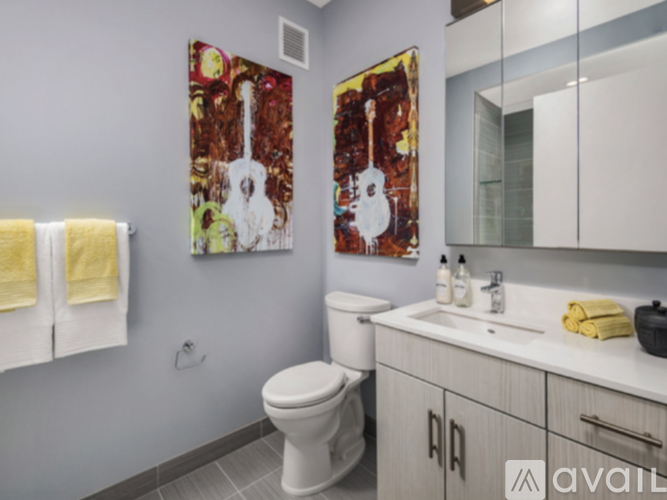 A bathroom with a white toilet and a painting of a guitar on the wall.