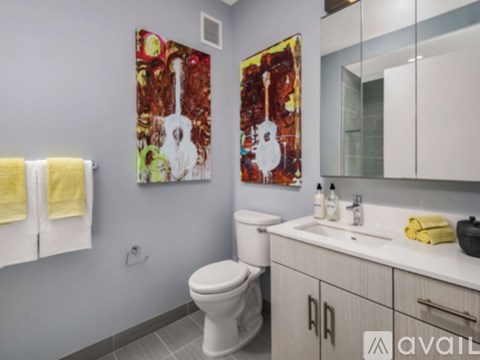 A bathroom with a white toilet and a painting of a guitar on the wall.