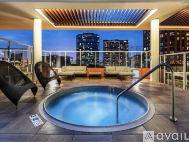 A hot tub on a balcony with a city view at dusk.