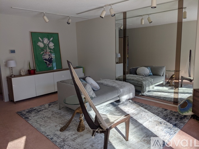 A bedroom with a bed, a chair, and a mirror.