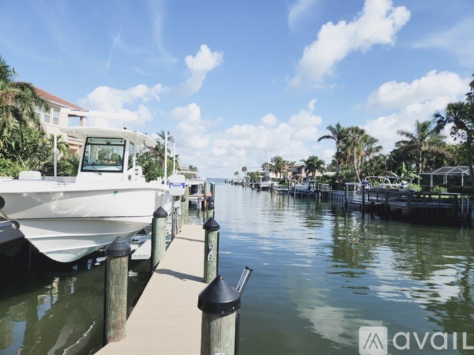 A boat is docked at a pier with a house and palm trees in the background.