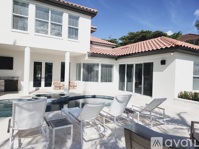 A white house with a pool and chairs.
