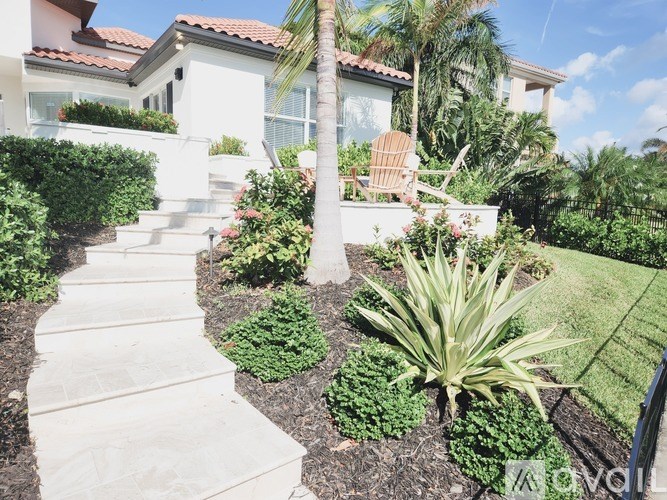 A white house with a red tile roof and a palm tree in front.