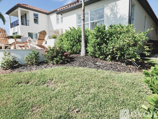 A white house with a red tile roof and a palm tree in front.