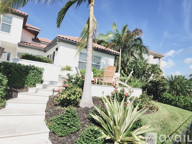 A white house with a palm tree in front.