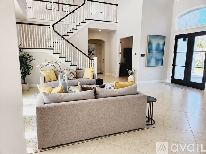 A living room with a grey couch and a staircase.