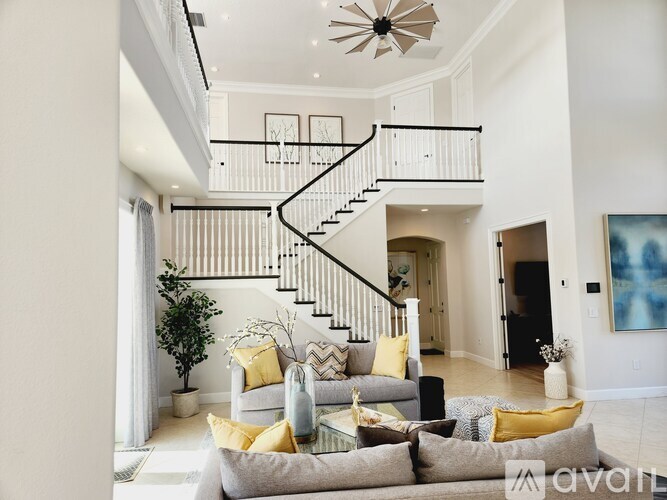 A living room with a staircase and a painting on the wall.