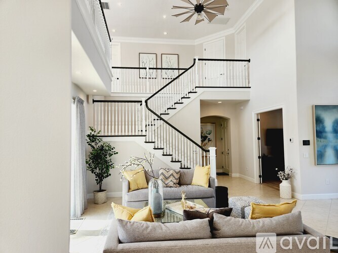 A living room with a grey couch and a staircase.