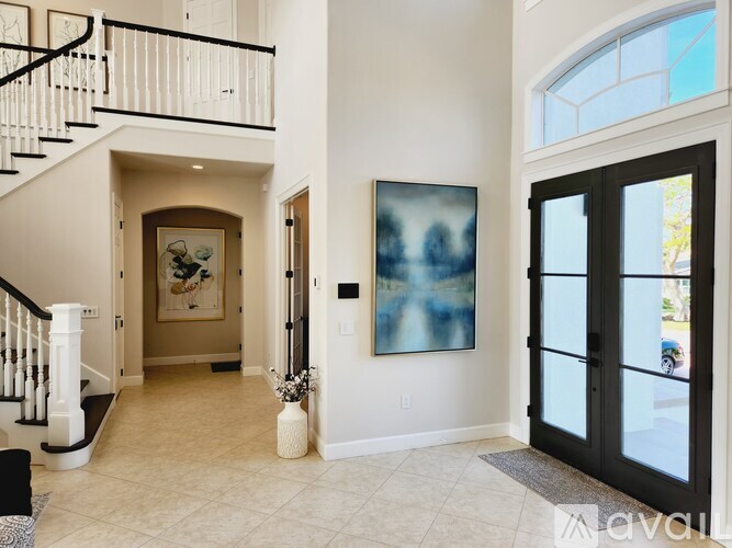 A hallway with a painting on the wall and a black door.
