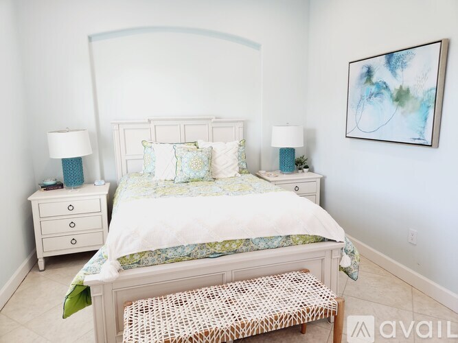 A bedroom with a large bed, two nightstands, and a painting on the wall.