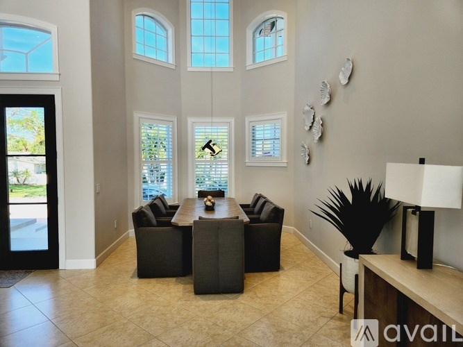 A living room with a black couch, a coffee table, and a large window.