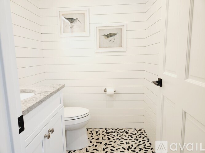 A bathroom with a toilet, sink, and pictures on the wall.