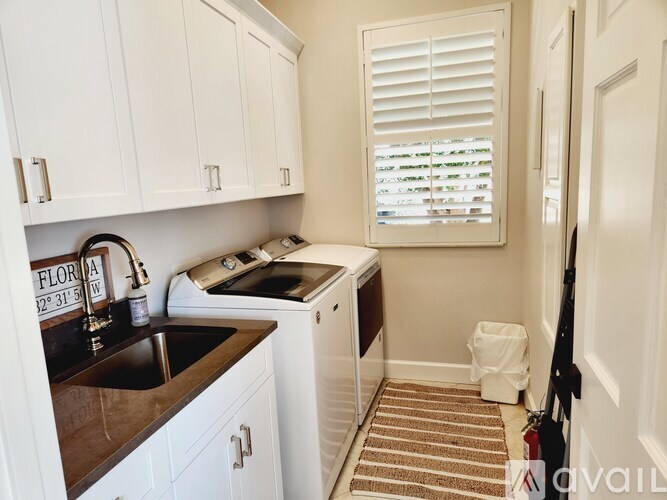 A small kitchen with white cabinets and a black counter top.