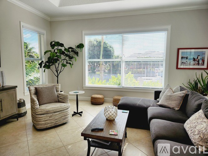 A living room with a grey couch, a wicker chair, and a wooden coffee table.