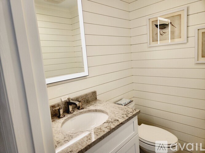 A bathroom with a sink, toilet, and a mirror.