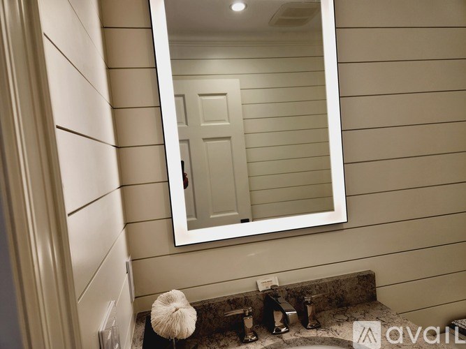 A bathroom with a mirror, sink, and towel.