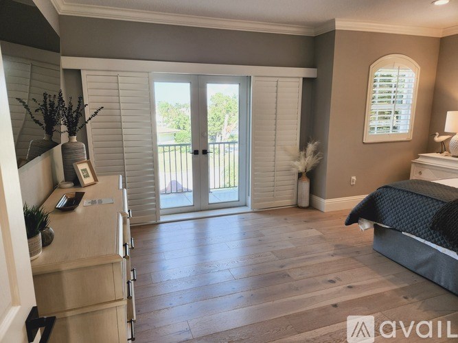 A bedroom with a bed, dresser, and sliding glass doors leading to a balcony.