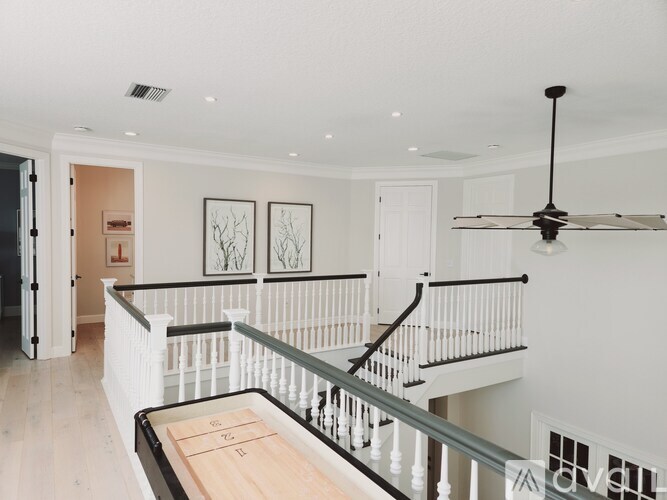 A white interior with a staircase and a ceiling fan.