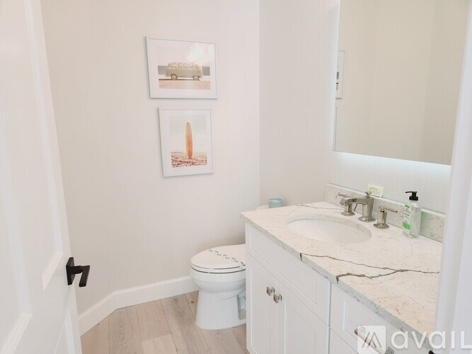 A bathroom with a toilet, sink, and two pictures on the wall.