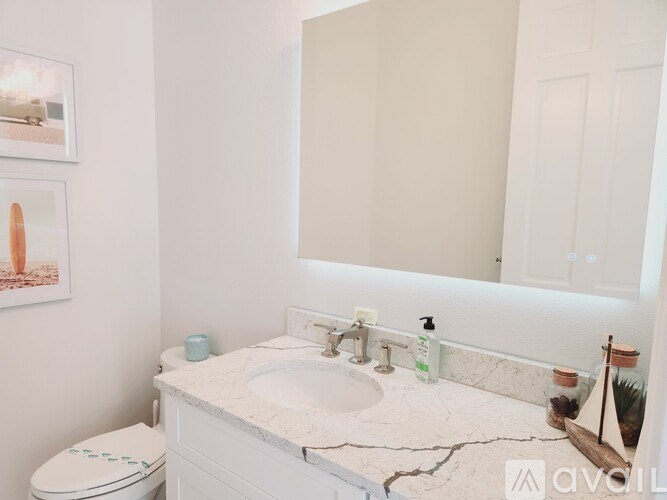 A white bathroom with a marble counter top and a toilet.