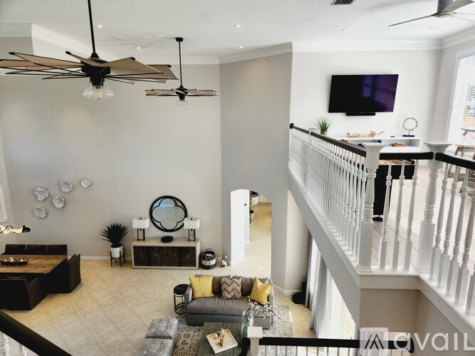 A living room with a white railing and a grey couch.