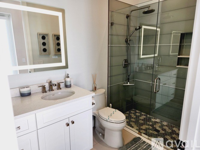 A white bathroom with a sink, toilet, and glass shower stall.