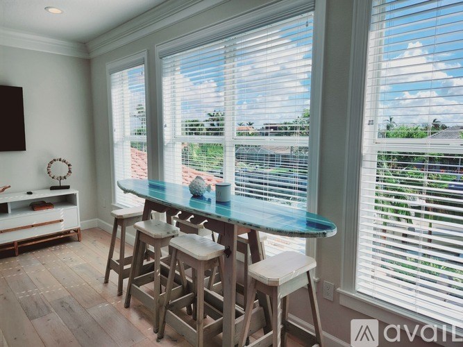A kitchen with a bar and stools in front of a window.