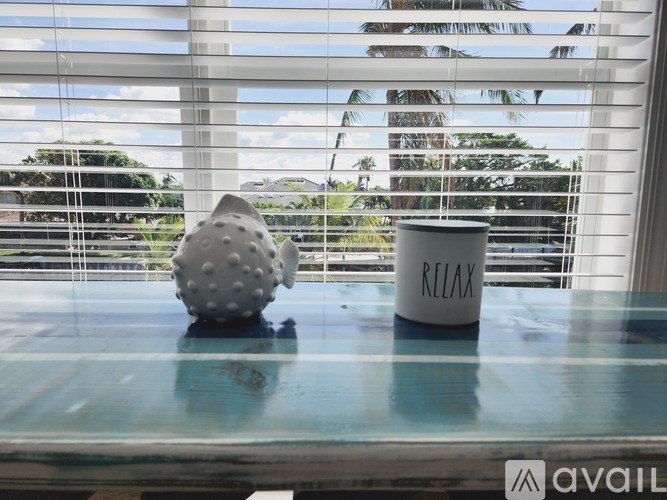 A white cup with the word RELAX on it sits on a table next to a grey ball.