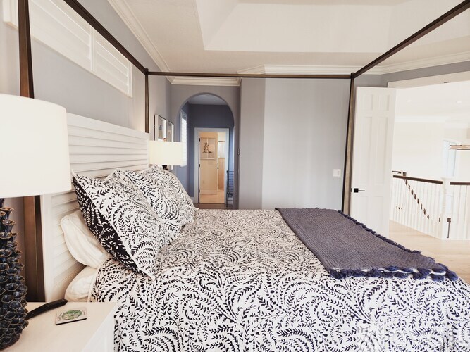 A bedroom with a large bed and a lamp on the side table.