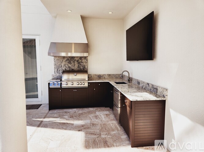 A modern kitchen with a stone backsplash and dark brown cabinets.