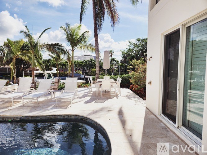A pool with chairs and palm trees in the background.