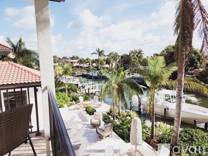 A balcony overlooks a marina with boats and palm trees.