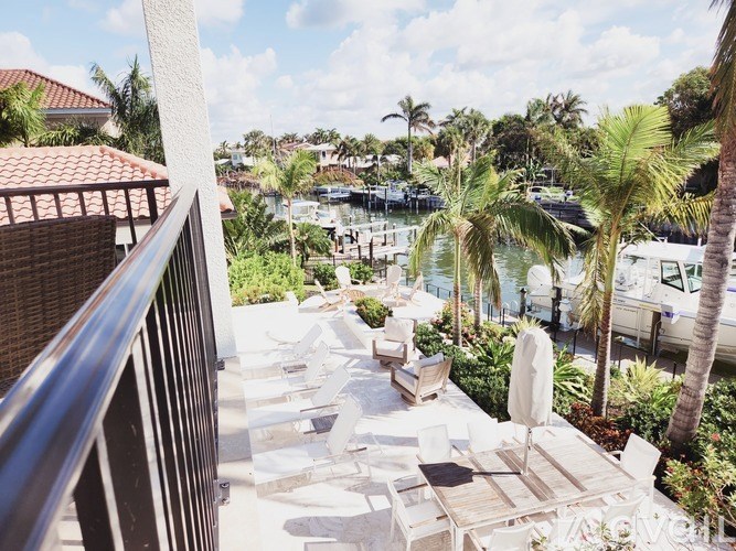 A balcony with white furniture overlooks a marina with boats.