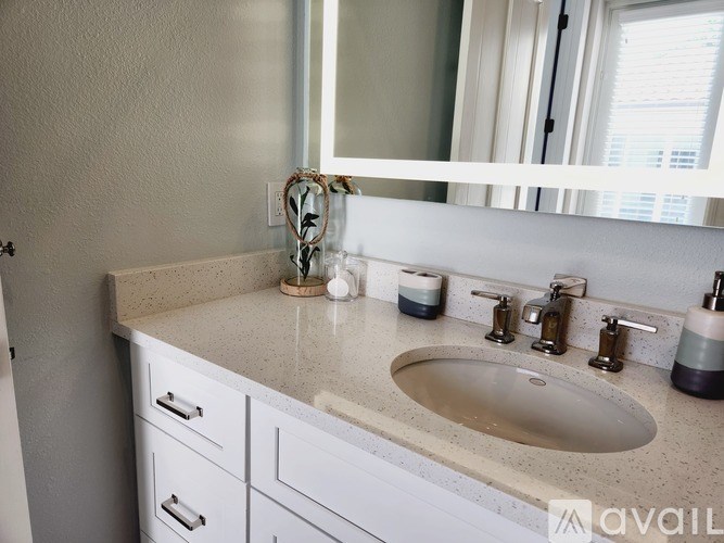 A bathroom with a sink, mirror, and white cabinets.