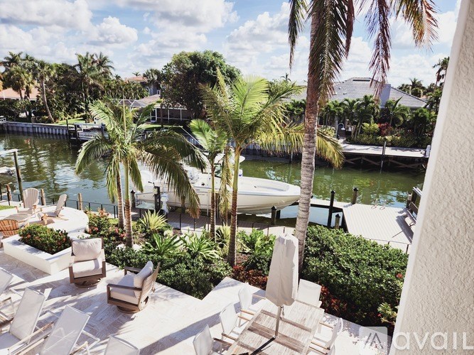 A patio with chairs and a table overlooking a body of water.