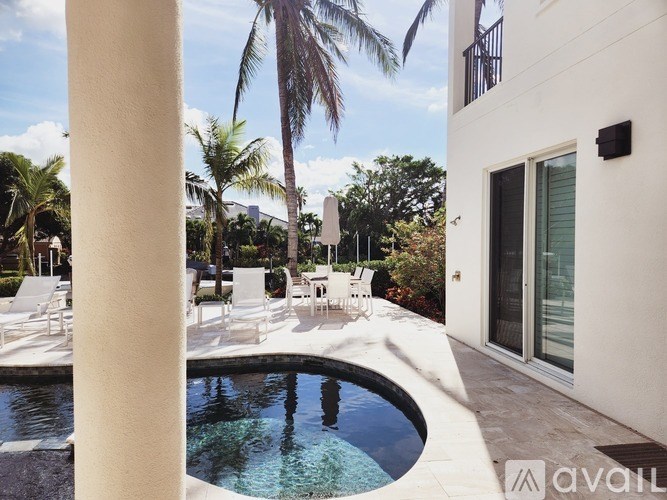 A pool surrounded by white chairs and palm trees.