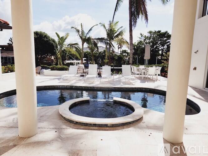 A pool surrounded by white chairs and palm trees.