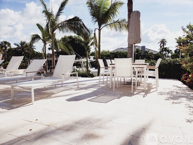 A row of white lounge chairs are arranged on a patio.