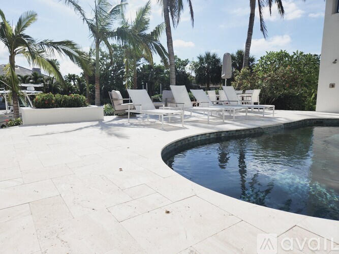 A pool surrounded by white chairs and palm trees.