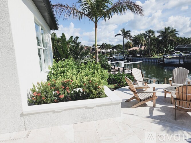A patio with chairs and a table overlooks a body of water.