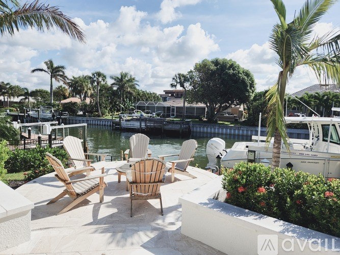 A patio with chairs and a table overlooking a body of water.