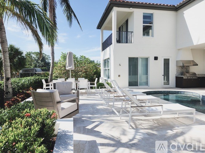A white house with a pool and lounge chairs.
