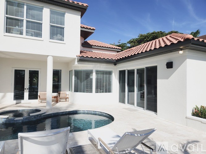 A white house with a red tile roof and a pool in the backyard.