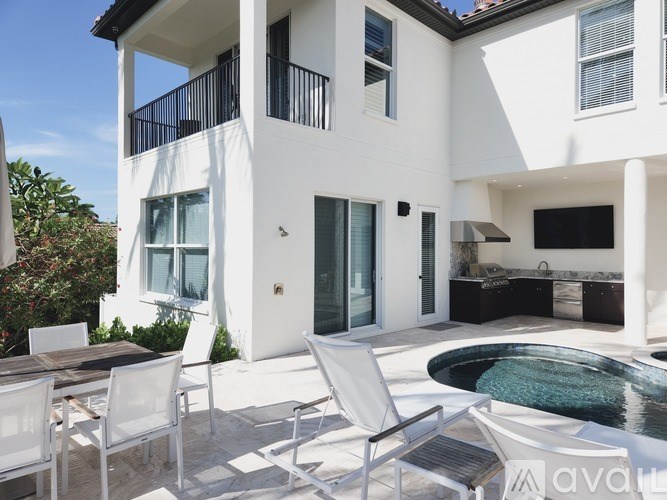 A white modern house with a pool in the backyard.