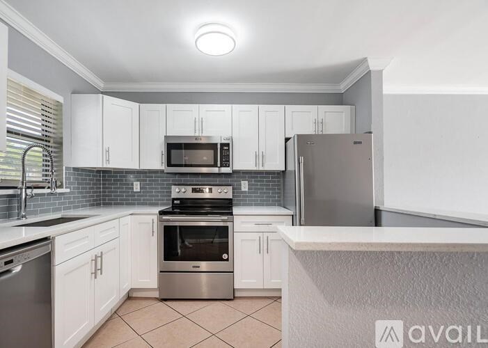 A kitchen with white cabinets and a stainless steel refrigerator.